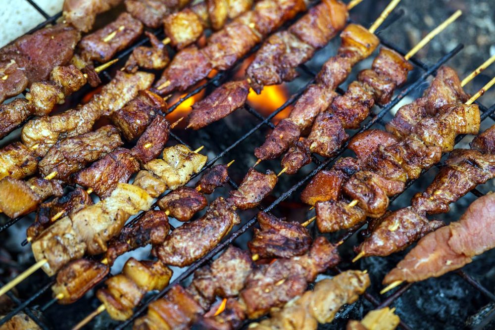 Skewers of grilled meat over charcoal