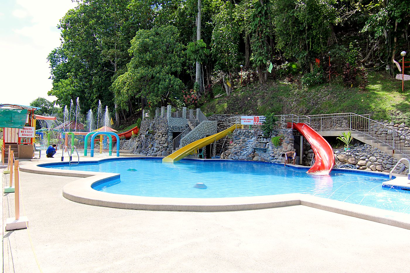 The kids' pool with two slides and fountains, with the hillside behind